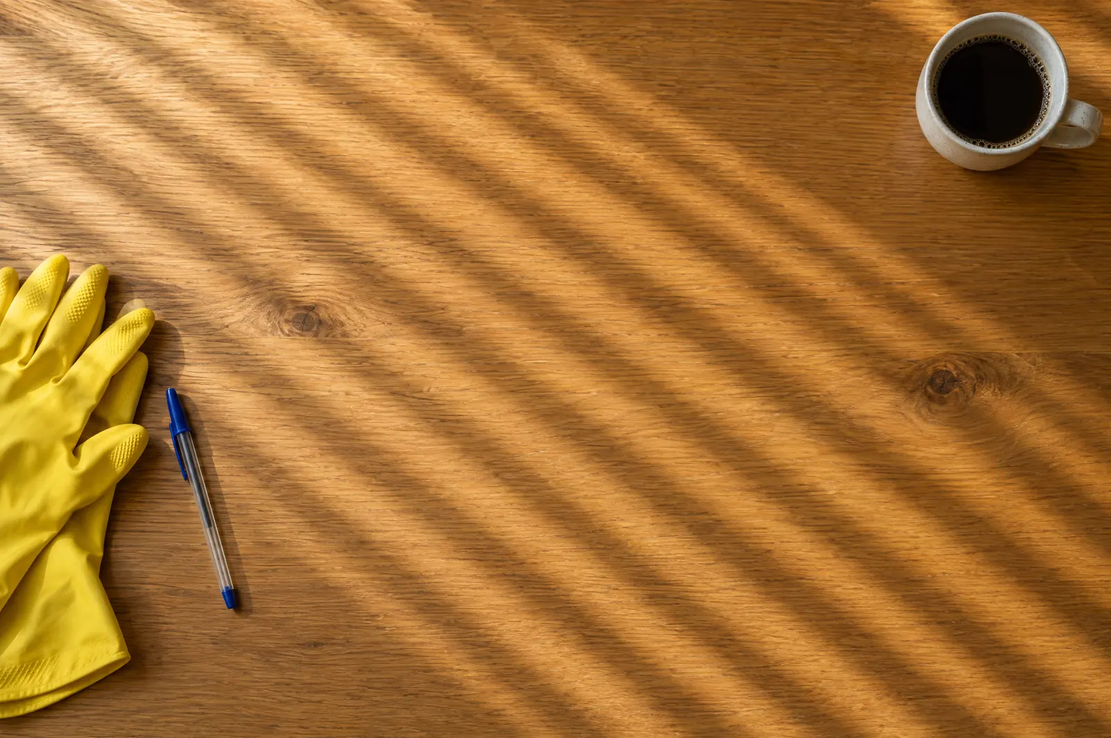 Holztisch mit Handschuhen und Kaffee im Morgenlicht